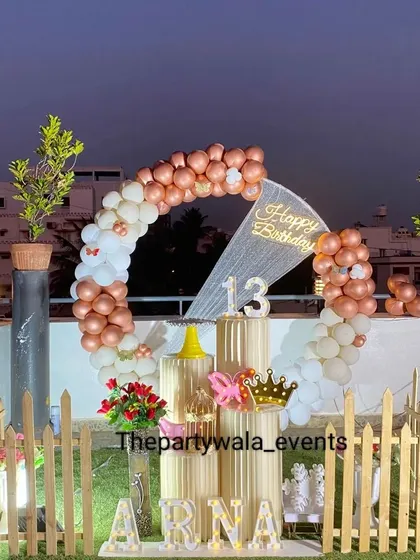 An outdoor rooftop party with a rose gold and white balloon ring, creating a stunning photo op against the city skyline.