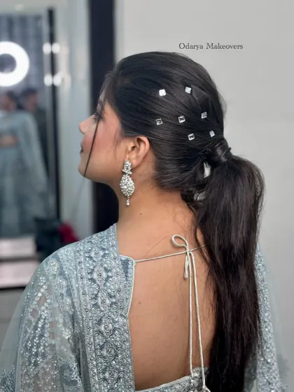 This trendy ponytail hairstyle is a great choice for a modern reception or cocktail look. The mirror-work accessories add a unique and glamorous touch.