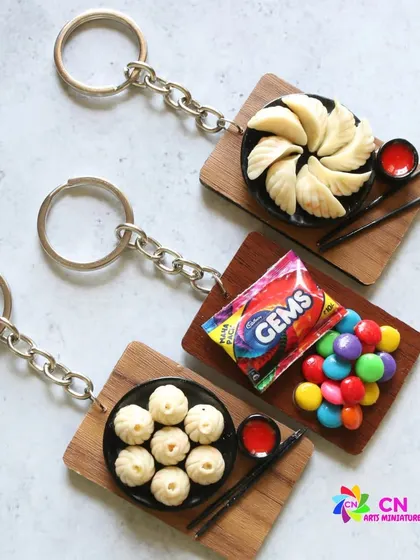 A collection of food keychains, including momos and Gems chocolates.