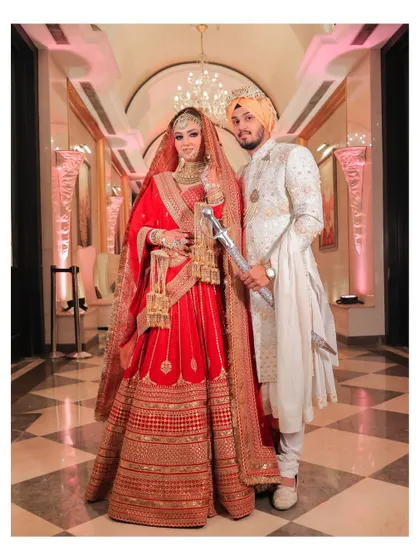 A full-length portrait of the Sikh couple in a grand, checkered-floor hallway. Their royal Sabyasachi outfits are showcased in all their glory.