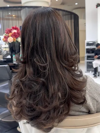 A classic coffee brunette transformation. The deep, rich color is enhanced by a layered haircut that creates beautiful shape and movement from the back.