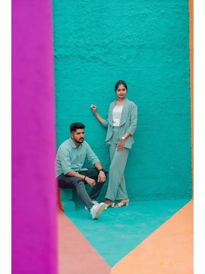 A modern and stylish shot of a couple against a vibrant, color-blocked wall. Their coordinated outfits and the bold background create a very artistic portrait.