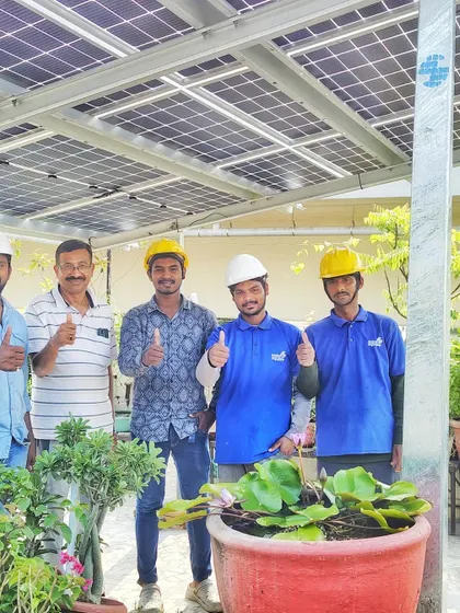 Our team and a happy customer give a thumbs-up in front of a newly installed solar system on a rooftop garden.