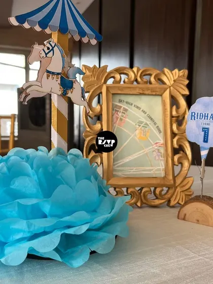 A delicate carnival-themed centerpiece with a mini carousel horse and a framed picture.