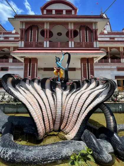 A sculpture of Lord Krishna dancing on the multi-headed serpent Kaliya, located in a water body at the ISKCON Pune temple complex.
