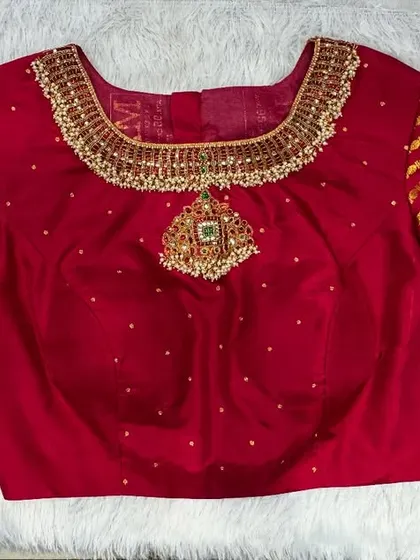 A bold red blouse with a jewelry-style neckline, featuring a heavy, necklace-like embroidered piece.