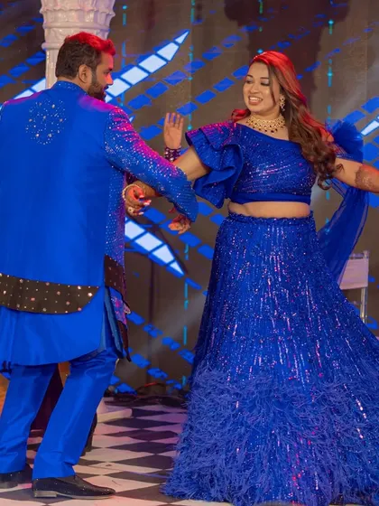 A candid moment of the couple dancing on their sangeet night. The joy and energy are infectious, and the dynamic lighting on the dance floor adds to the celebratory mood.