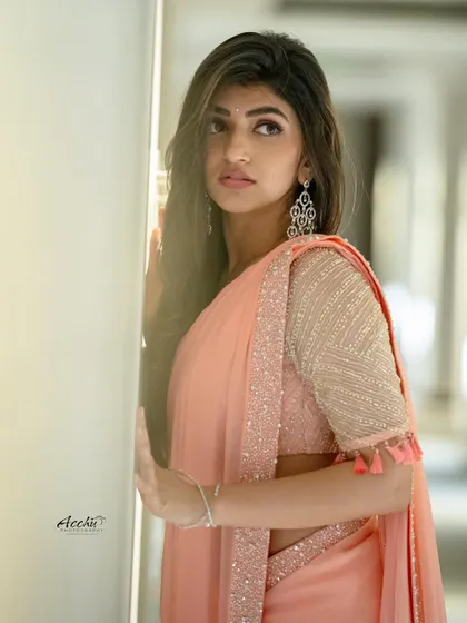 Soft and ethereal. This portrait uses natural light from a window to create a gentle, glowing effect on the peach-colored saree, emphasizing a quiet and graceful mood.