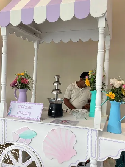 A chocolate fountain cart decorated in pastel mermaid colors.