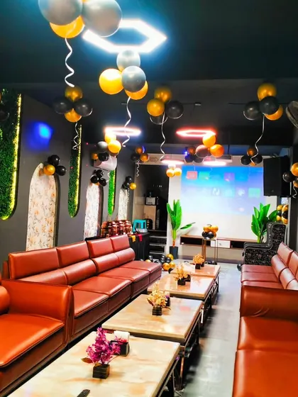 A stylish black and gold balloon decoration in a private party room. Balloons are hung from the ceiling, complementing the venue's modern and dark interior.