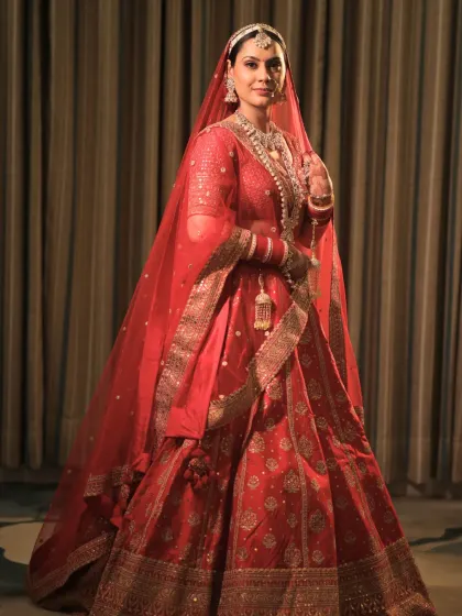 A full-length portrait of this bride in her timeless red lehenga. The makeup was crafted to exude elegance and grace, with a radiant glow that enhances her natural beauty.