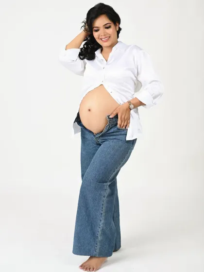 A confident and happy solo portrait. The mom-to-be's relaxed pose and bright smile shine in this casual, modern look.