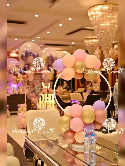 A modern and chic table centerpiece featuring a white hoop adorned with pastel balloons, perfect for a stylish butterfly or fairy-themed party.