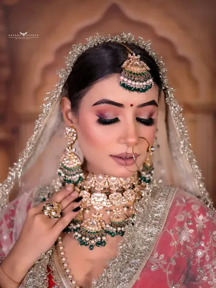 A close-up shot from a high angle, focusing on the bride's expressive eyes and the intricate details of her maang tikka and necklace.