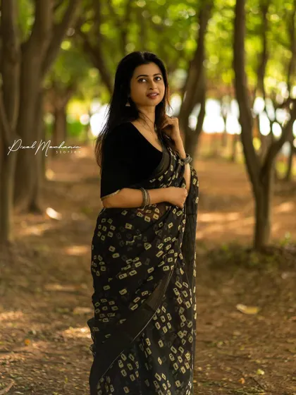 A full-length portrait showcasing the elegance of a black saree against the rustic backdrop of a park. The contrast between the traditional attire and the natural setting creates a beautiful visual story.