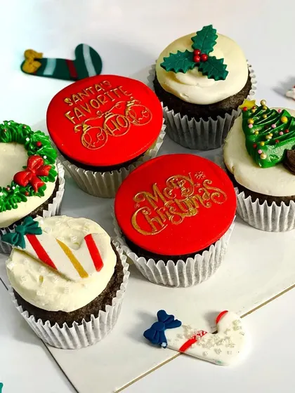 Getting into the Christmas spirit with my custom cupcakes. This box of six features rich chocolate cupcakes decorated with festive designs like a wreath, candy cane, and "Merry Christmas" fondant toppers.