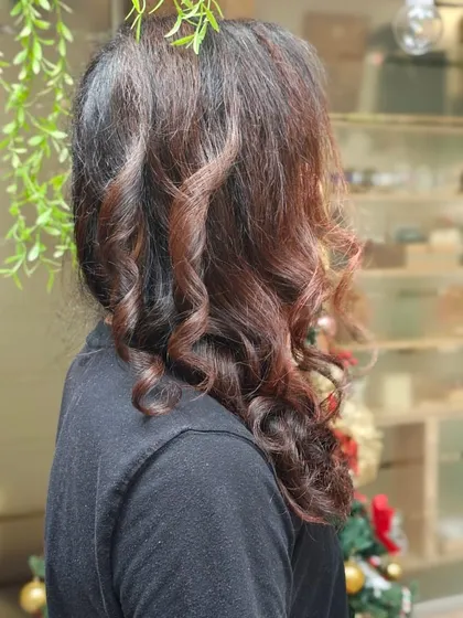 A side profile of a men's style, showcasing expertly crafted curls and a rich, subtle colour that adds dimension and character to long hair.