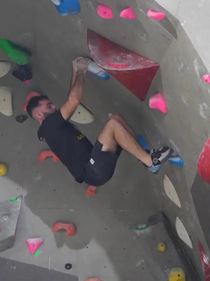 Adventure is just a grip away. This climber is fully engaged, using core strength to navigate an overhanging section of our wall. Our routes are designed to challenge you and make you stronger.
