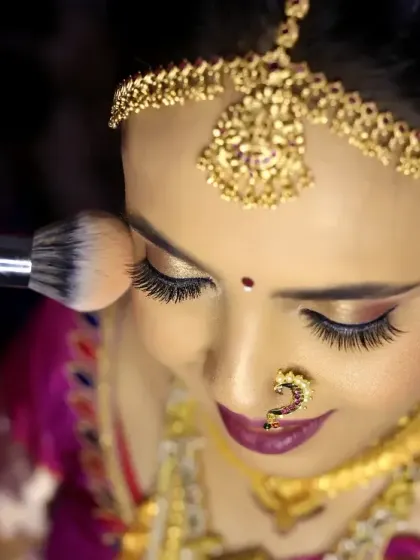 A detailed shot of the bride's makeup being applied, focusing on the artistry and the final touches that complete her look.
