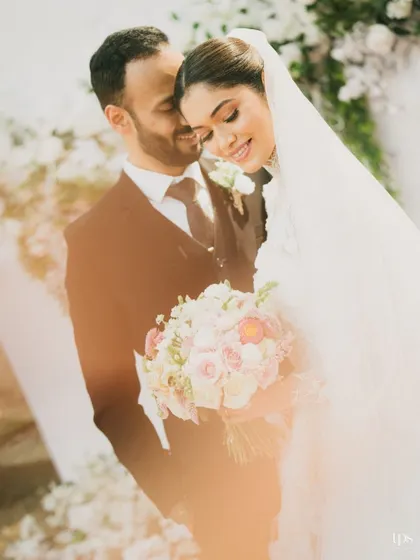 A soft and dreamy portrait of the couple, bathed in a warm, golden light. The bride holding her bouquet adds a classic touch to this romantic image.