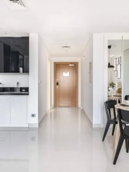 A render of a bright and clean entryway and kitchenette for a studio apartment, demonstrating a smart and efficient use of space.