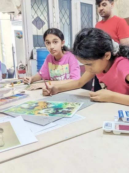 An instructor observing and guiding two students as they work on their drawings. This constant interaction and feedback loop is central to our teaching method.