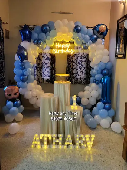 A Boss Baby theme for a first birthday at home, featuring a blue and white balloon arch and light-up letters.