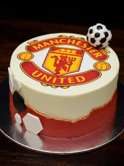 A cake for a true Manchester United fan. This design features the team's logo as an edible print, a fault-line design in the club's red color, and a small fondant football on top.
