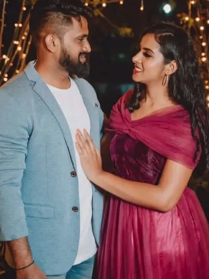 A close up of the couple under the fairy lights, showing the draped top of the maroon gown.