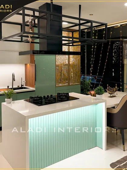 A view of the kitchen island at night, with the under-counter and overhead lighting creating a dramatic and inviting ambiance. The fairy lights outside the window add a magical touch.