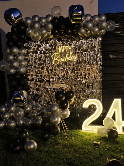 A nighttime shot of the 24th birthday silver sequin wall, showing how the lights and balloons create a festive party atmosphere.