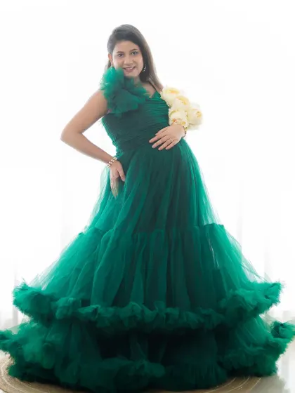 A stunning high-key portrait of a mom-to-be in a vibrant green ruffled gown. The bright lighting creates an angelic and ethereal feel.