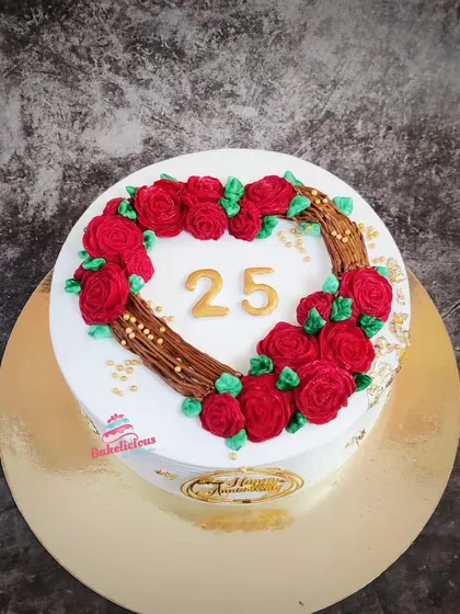 A lovely cake for a 25th anniversary, featuring a heart-shaped wreath made of tiny red buttercream roses.