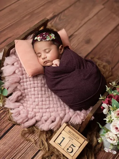 An overhead shot of the baby wrapped in purple, sleeping in her tiny bed.
