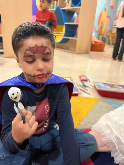 This little vampire is admiring his finished ghost lollipop. The face paint and costumes make our Halloween party extra special.
