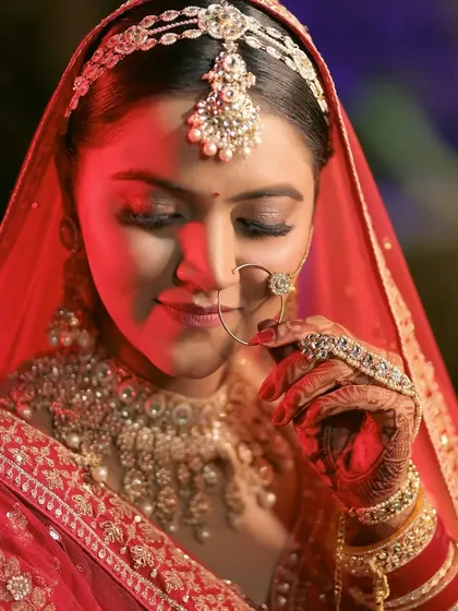 A close-up bridal portrait focusing on her serene expression and traditional jewelry. The soft lighting and her gentle pose create a feeling of timeless elegance.