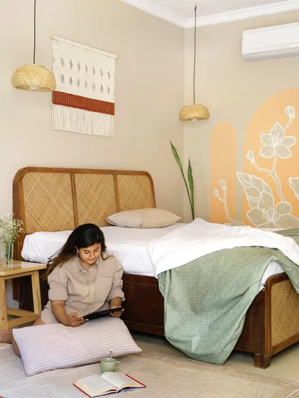 The bedroom at Unallome is a sanctuary of calm. Here, our founder Ritika Rakhiani enjoys the serene atmosphere she designed, which features a cane bed, macrame wall hangings, and a soft, earthy color palette.