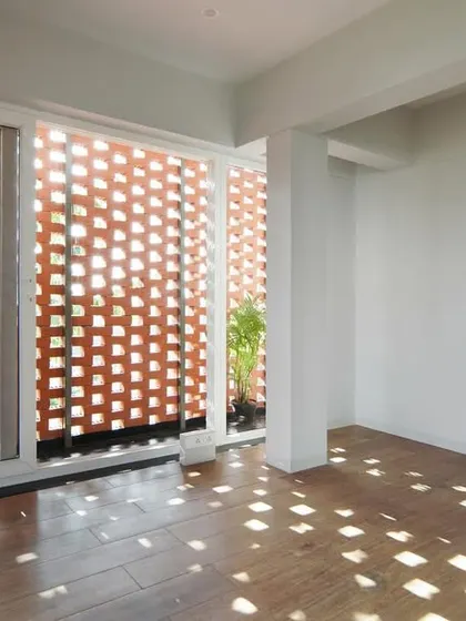 The play of light through the brick *jali* screen is a key feature of the design. The sunlight projects a moving pattern onto the wooden floor, making the space feel alive.
