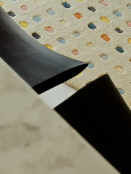 A close-up detail showing the texture of a colorful rug and the leg of a marble table. It's these small moments of beauty that make a house feel special.