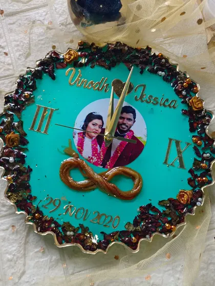 This clock features a teal background with a full border of preserved flowers and a preserved thali. The couple's photo is in the center, making it a truly personal keepsake.