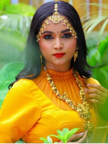 A stunning close-up portrait of a client in a yellow half saree with a high-neck blouse and traditional matha patti.