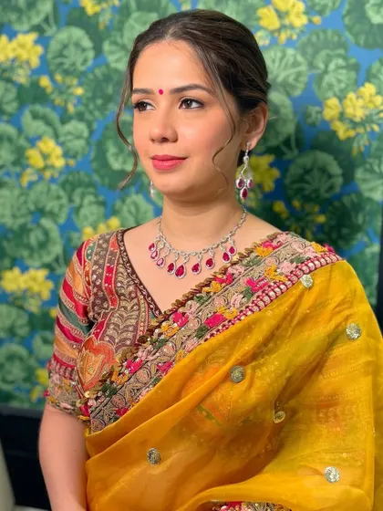 A three-quarter view of this elegant look. The soft makeup complements the rich yellow of her saree and the intricate border.