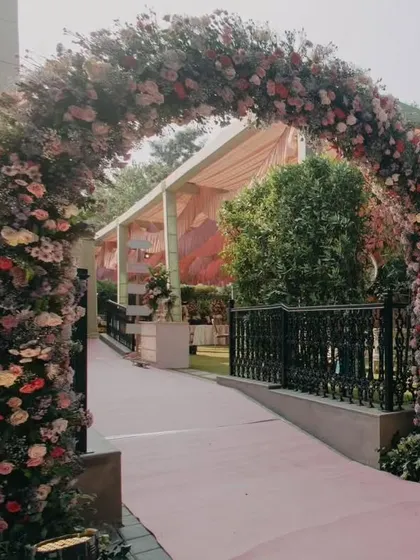 A grand floral arch in pastel shades marks the entrance to the Mehendi venue, setting a soft, romantic, and welcoming tone for the daytime celebration.