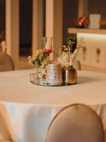 A close-up of a table centerpiece from the royal-themed engagement. The design includes delicate florals, candles, and metallic vases on a mirrored base to reflect the ambient light beautifully.