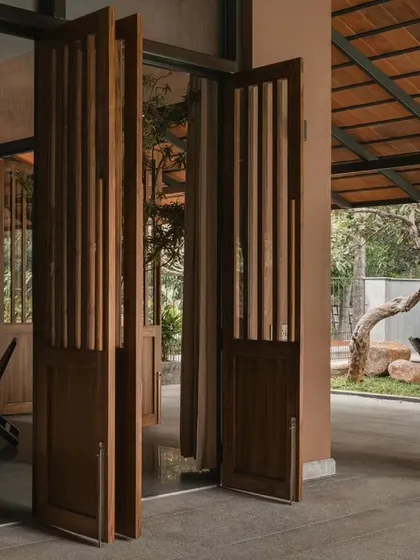 Detail of the foldable wooden doors that open from an interior room to a covered veranda. This feature allows for flexible use of space, easily adapting from a private room to an open, connected area.