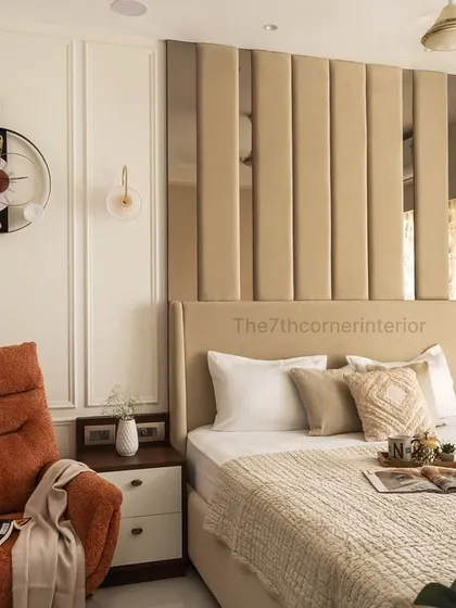 A wider view of the bedroom, showing the plush burnt-orange lounge chair that creates a cozy reading nook. The neutral tones and warm ambient lighting contribute to a comfortable and modern space.
