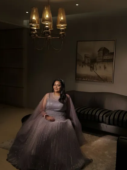 A full-length portrait in a moody, elegant setting. The soft glam makeup and sparkling gown create a timeless and sophisticated look.