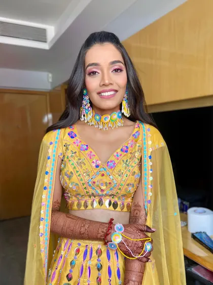 A portrait of the happy bride-to-be at her Haldi ceremony. The makeup is vibrant and fun, perfect for the occasion.