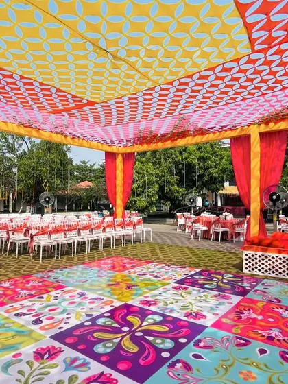 A vibrant and colorful setup for a Mehendi or Haldi party. The custom-printed dance floor and the patterned ceiling canopy create a fun and energetic atmosphere.