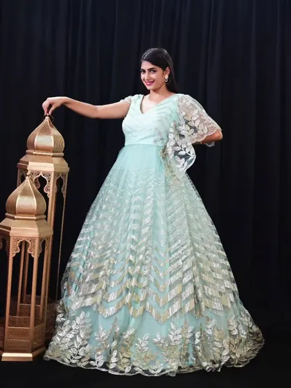 This light blue gown with gold leaf embroidery and a cape sleeve is a unique and elegant rental choice.